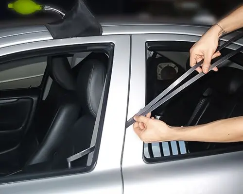 A Technician Is Using A Long-Reach Tool To Unlock A Car Door From The Outside.