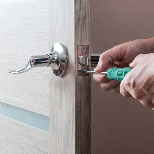 A House Locksmith Is Installing A Lever Handle Lock On A Wooden Door.