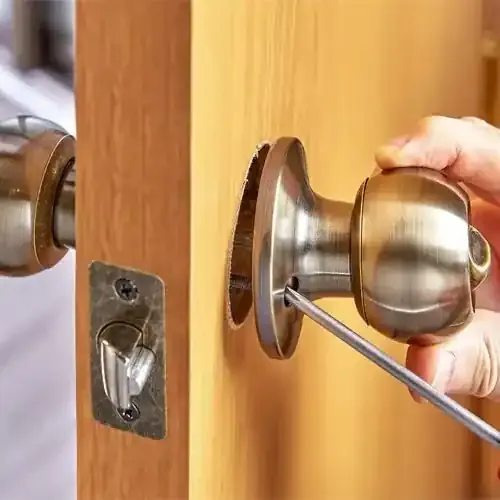 A Locksmith Technician Is Installing A Doorknob Lock On A Wooden Door.