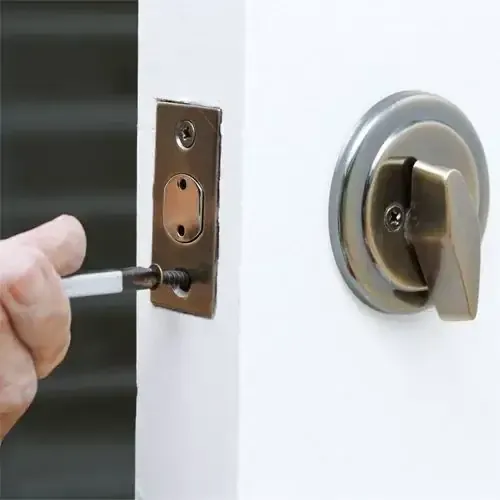 A Locksmith Technician Is Installing A Deadbolt Lock On A White Door.